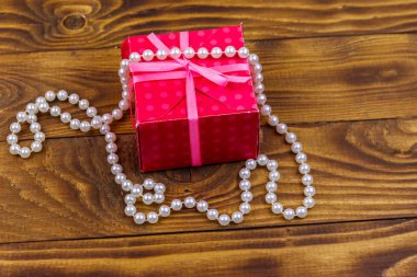 Ahşap arka planda hediye kutusu ve inci kolye.