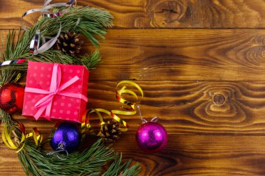 Noel kompozisyonu köknar ağacı dalları, hediye kutusu ve Noel süslemeleri ahşap masada. Üst görünüm, alanı kopyala