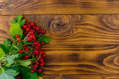 Ahşap masa üzerinde yeşil yaprakları ile kırmızı viburnum çilek. Üstte görüntü