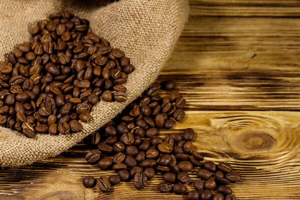 Roasted coffee beans on sackcloth on wooden table