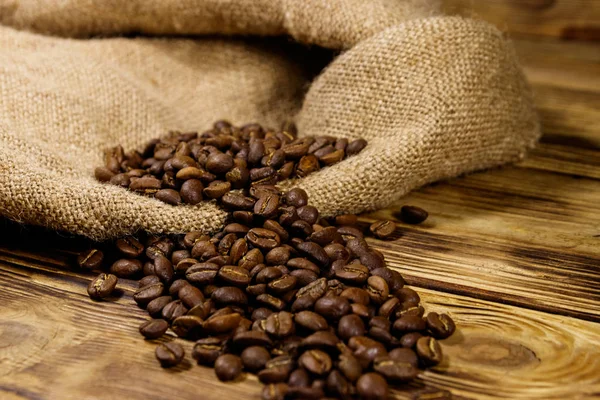 Roasted coffee beans on sackcloth on wooden table Stock Picture