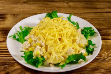 Tavuk göğsü, tatlı mısır, konserve ananas, peynir ve ahşap masada mayonez ile Şenlikli salata