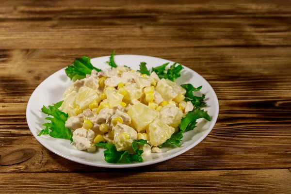 Праздничный салат с куриной грудью, сладкой кукурузой, консервированным ананасом и майонезом на деревянном столе — стоковое фото