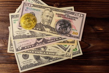 Ahşap masada altın ve gümüş bitcoinler ve dolar banknotları