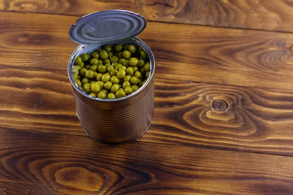 Open tin can of green peas on wooden table — Stock Photo, Image