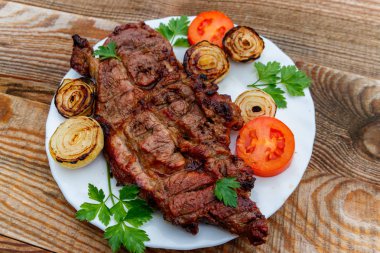 Beyaz tabakta soğan, domates ve maydanoz ile ızgara domuz eti 