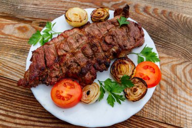 Beyaz tabakta soğan, domates ve maydanoz ile ızgara domuz eti 