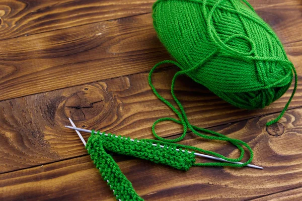 Balle de fil et aiguilles à tricoter avec tricot sur table en bois — Photo