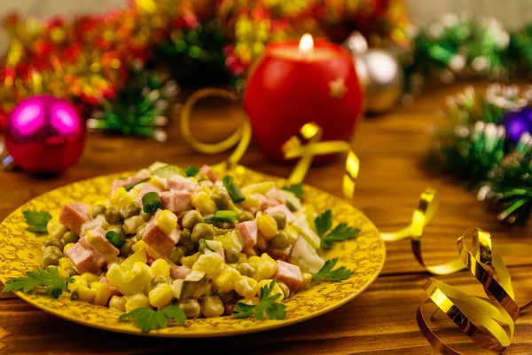 Sabrosa ensalada festiva, decoración de Navidad y vela en la mesa de madera — Foto de Stock