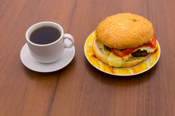 Delicious hamburger and cup of coffee on wooden table — Stock Photo, Image