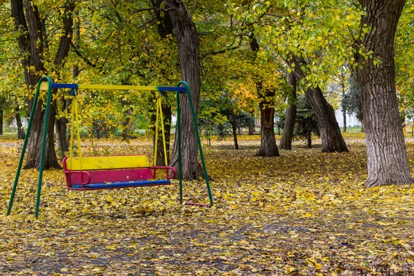 Empty children's swing in city park on autumn — Stock Photo, Image
