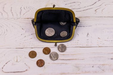 Beyaz ahşap arka planda birkaç bozukluk bulunan eski bozuk para çantası.. 