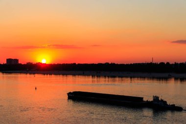Römorkör, gün batımında Dinyeper nehrinde ağır, uzun bir mavnayı itiyor.