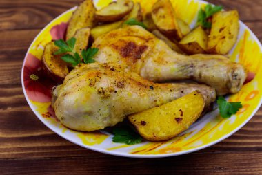 Ahşap masa üzerinde bir tabakta patates ile Fırında tavuk baget