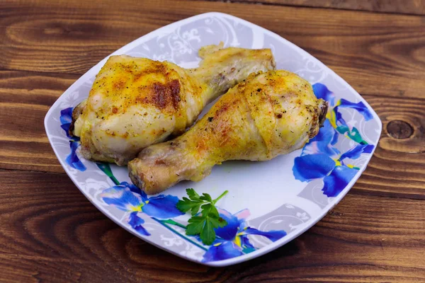 Gebakken kip drumsticks met aardappelen in een bord op houten tafel — Stockfoto