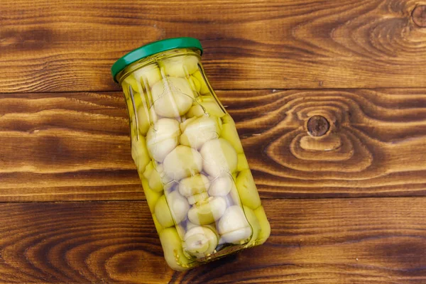 Deliciosos cogumelos marinados em frasco de vidro na mesa de madeira — Fotografia de Stock