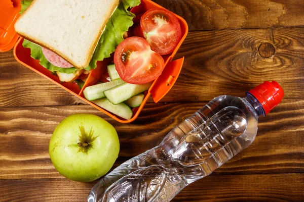 Pranzo scolastico con panino e verdure fresche, bottiglia d'acqua e mela verde sul tavolo di legno. Un concetto di alimentazione sana. Vista dall'alto — Foto Stock