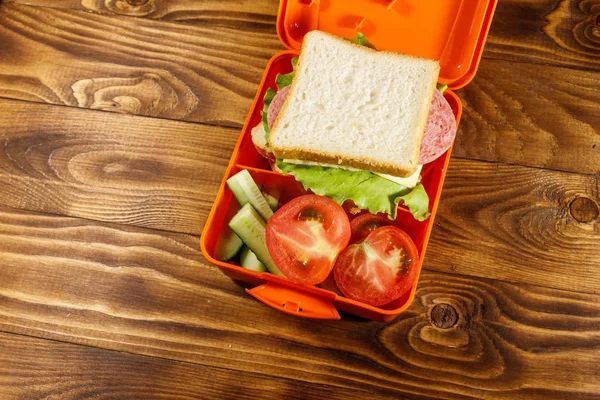 Szkoła pudełko na lunch z kanapkami i świeże warzywa na drewnianym stole. Widok z góry — Zdjęcie stockowe