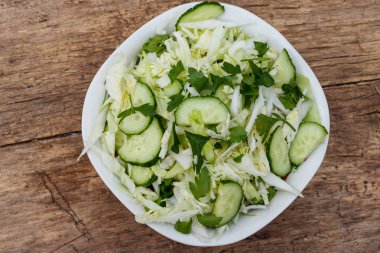 Bahar vegan salata lahana, salatalık, yeşil soğan ve maydanoz ahşap masa üzerinde. Üstten görünüm