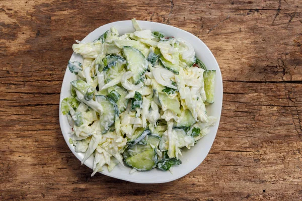 Ensalada de primavera con repollo, pepino, cebolla verde, perejil y mayonesa sobre mesa de madera. Vista superior —  Fotos de Stock