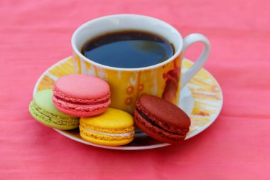 Pembe arka planda lezzetli renkli makarnalar ile kahve Fincan