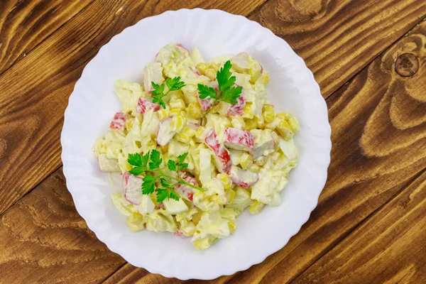 Salade avec bâtonnets de crabe, maïs doux, chou chinois, œufs et mayonnaise sur table en bois — Photo