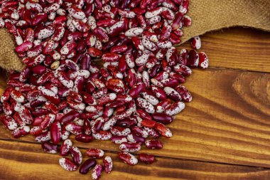 Ahşap masada çuval üzerinde çiğ barbunya fasulyesi