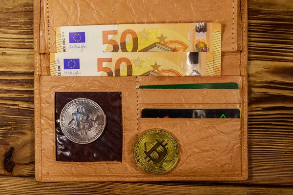 Pénztárca ötven euróval és bitcoinnal fából készült háttérrel — Stock Fotó