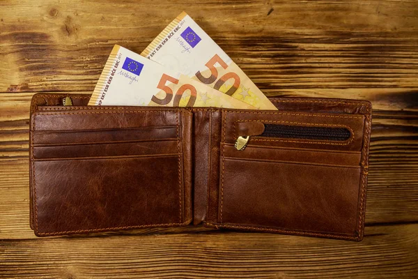 Open wallet with fifty euro banknotes on wooden background