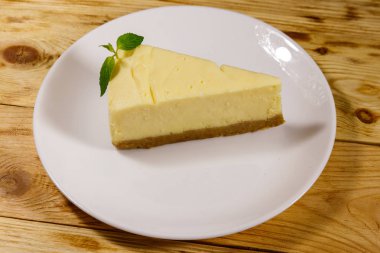 Ahşap masa beyaz bir tabağa lezzetli tatlı New York cheesecake parçası