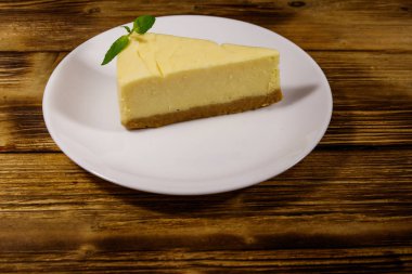 Ahşap masa beyaz bir tabağa lezzetli tatlı New York cheesecake parçası