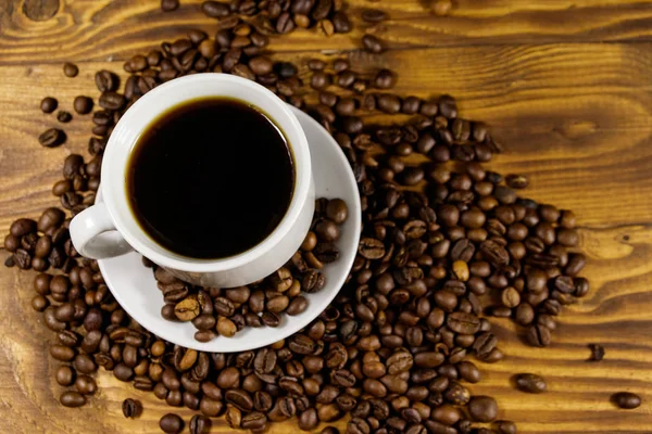 stock image Cup of coffee and roasted coffee beans on wooden table. Top  view