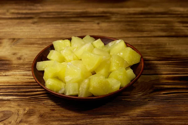 Canned pineapple pieces in ceramic plate on wooden table