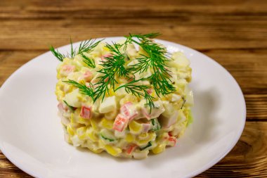 Yengeç çubuklu salata, tatlı mısır, salatalık, yumurta ve mayonez ahşap masada.