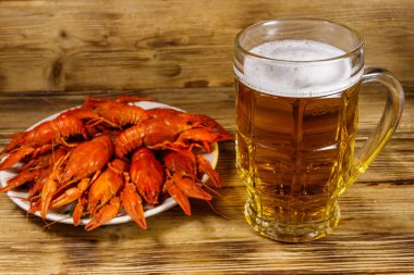 Haşlanmış kerevit ve bir kupa bira ahşap masada.