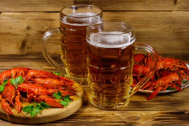 Haşlanmış kerevit ve tahta bir masada iki kupa bira.
