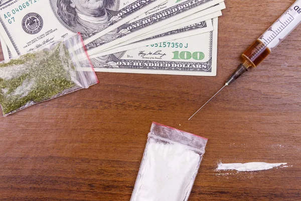 Diferentes tipos de drogas: cocaína, jeringa de heroína y cannabis seco y dólares en una mesa. Uso de drogas, tráfico de drogas, delincuencia y concepto de adicción —  Fotos de Stock