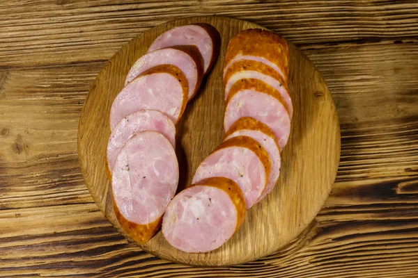 Salsicha fumada fatiada na tábua de corte na mesa de madeira — Fotografia de Stock