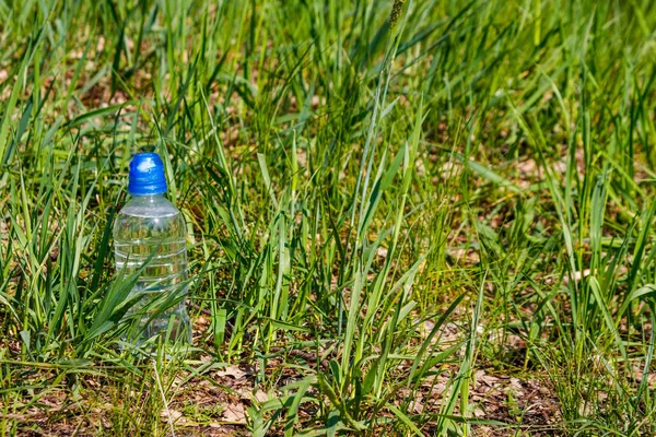 Garrafa de plástico com água potável fresca em grama verde no prado — Fotografia de Stock