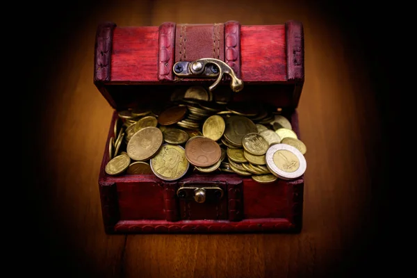 Vintage treasure chest full of golden coins on wooden background