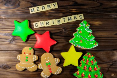 Lezzetli Noel kurabiyeleri ve ahşap masaya yazılmış Mutlu Noeller. Üst görünüm