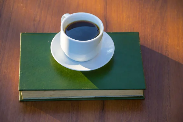 Taza de café y libro sobre mesa de madera — Foto de Stock