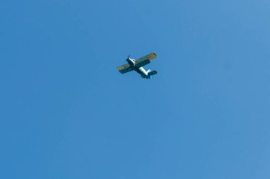 Mavi gökyüzünde uçan çift kanatlı uçak