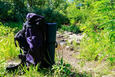 Yaz aylarında bir nehir yakınında turist sırt çantası. Zam konsepti