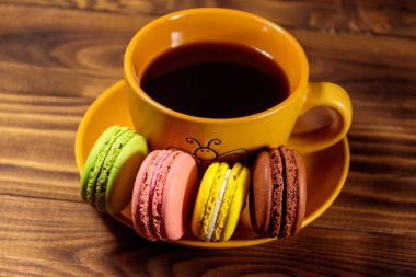Bir fincan kahve ile lezzetli renkli macarons ahşap masa üzerinde. Üstten görünüm