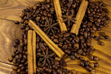 Kavrulmuş kahve çekirdekleri, tarçın çubukları ve ahşap arka planda yıldız anason.