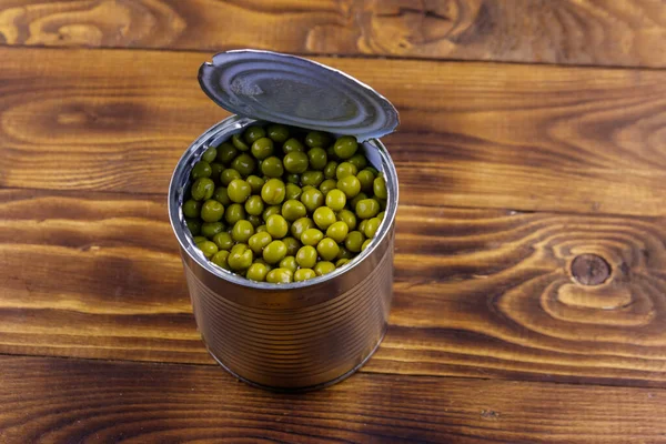 木製のテーブルの上に緑のエンドウ豆のオープン錫缶 — ストック写真