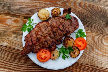 Izgara domuz etli soğan, domates ve maydanoz ahşap masa üzerinde beyaz plaka