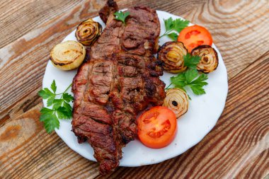 Izgara domuz etli soğan, domates ve maydanoz ahşap masa üzerinde beyaz plaka