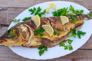 Ahşap masada limon ve maydanoz ile pişmiş sazan balığı